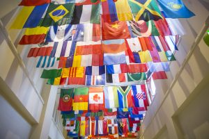 Multiple international flags hang from a ceiling in a spacious, well-lit room.