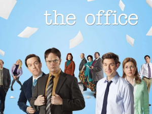 Cast of a TV show standing together with papers flying around against a blue background, with the title "The Office" at the top.