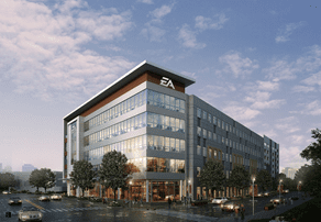 A modern office building with large windows under a partly cloudy sky, featuring the EA logo on the facade. Cars are parked along the surrounding street.