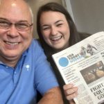 Two people smiling. The person on the right holds a USA Today newspaper with the headline "Fight for Equality Goes On.