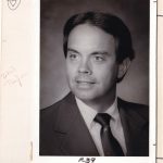 Black and white portrait of a man in a suit, looking to the side. Handwritten notes, including "R39," are on the border.