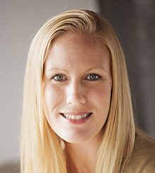 A person with long blonde hair smiles at the camera.