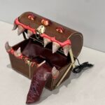 A treasure chest with large teeth and eyes, resembling a monster, with a red tongue extending outward.