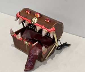 A treasure chest with large teeth and eyes, resembling a monster, with a red tongue extending outward.