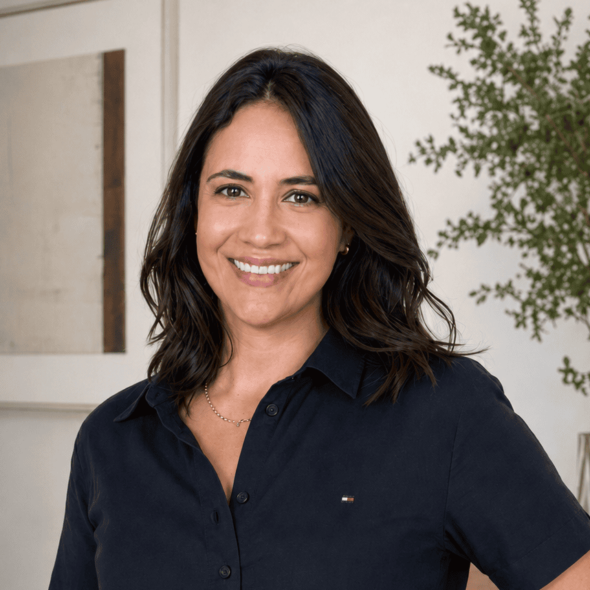 A smiling woman with dark hair wearing a navy button-down shirt and beige trousers.